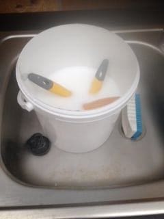 paint brushes in a bucket filled with painty water