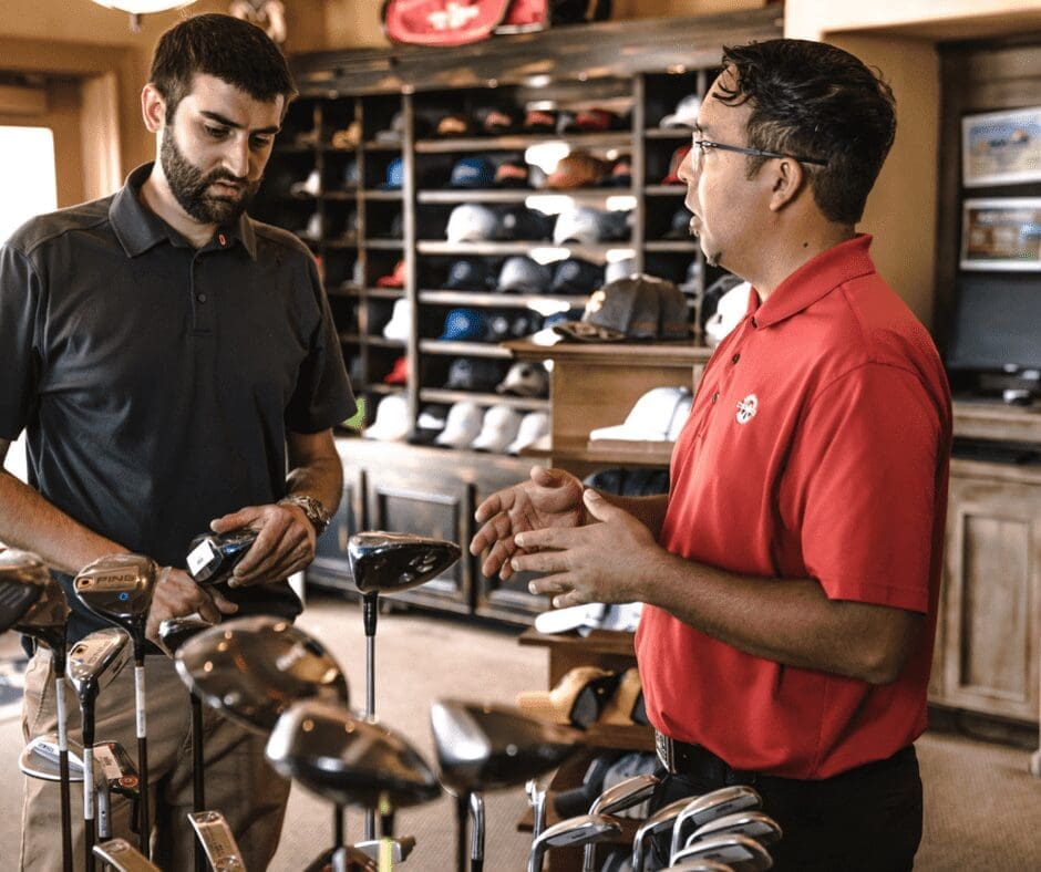 man and sales assistant talking over golf clubs