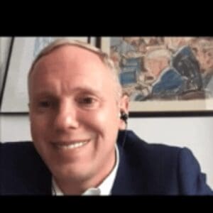 White man a little light coloured hair on zoom call smiling picture behind him