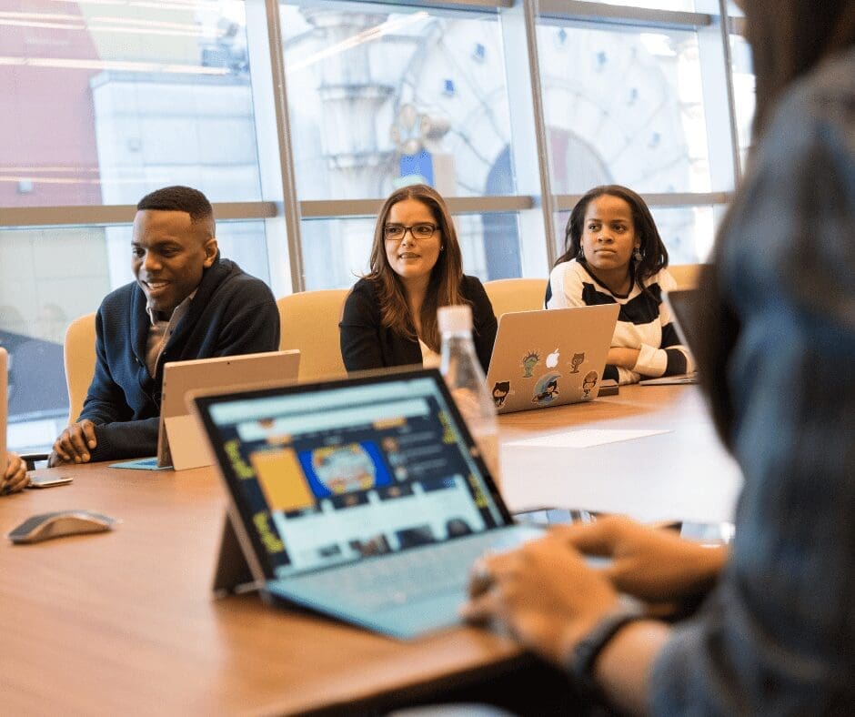 people sitting round table with laptops