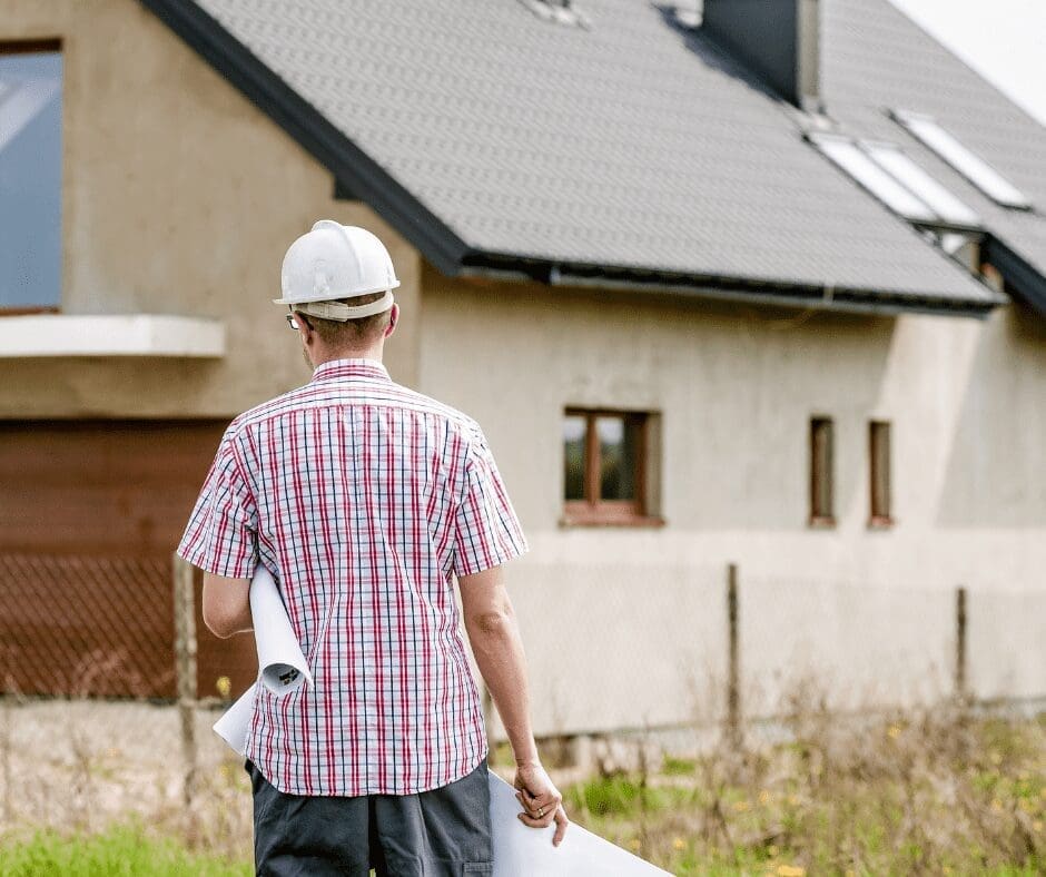 man with checked shirt back to camera white hard hat walking towards house