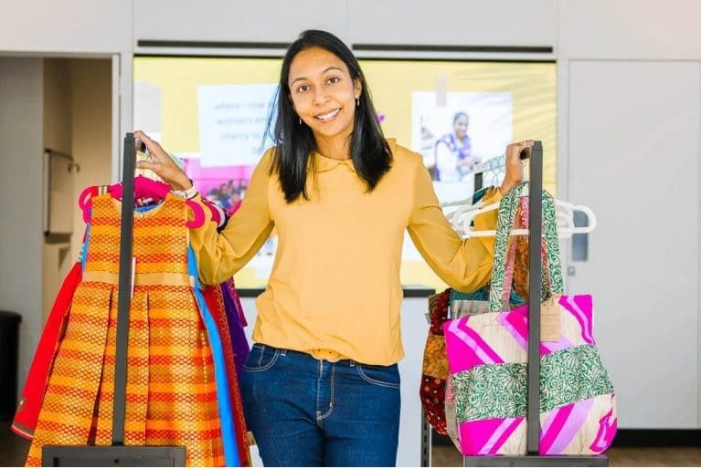Priya standing between 2 rails of clothes