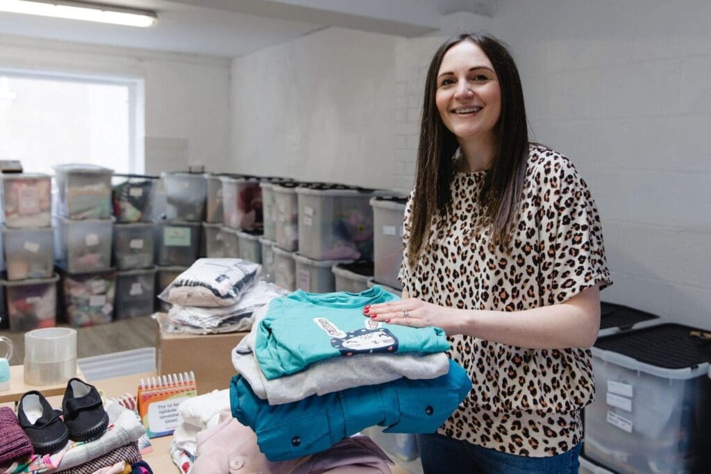 Anna Caragon with pile of second hand clothes