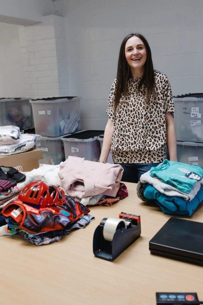 Anna Caragon behind table with piles of folded clothes