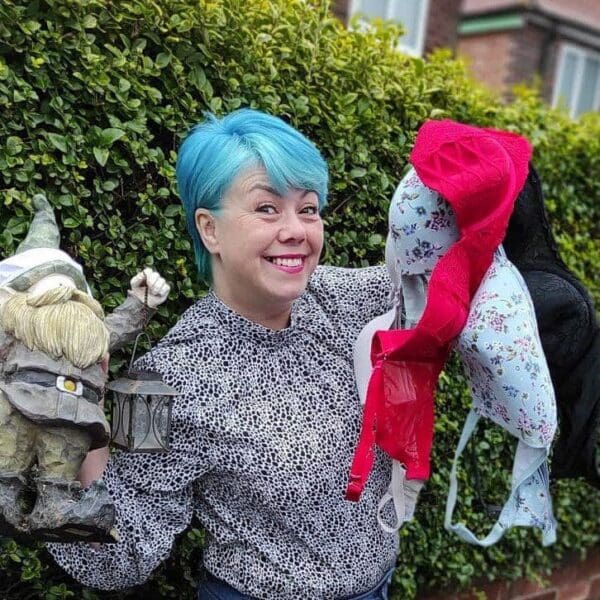 Janine with blue hair holding up bras