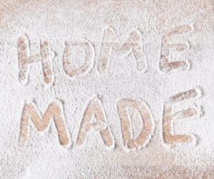 Flour on a table with the words "Home" and Made" made in the flour