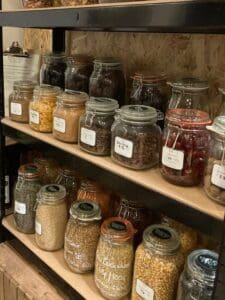 Two wooden shelves with kilner jars full of seeds, pulses etc