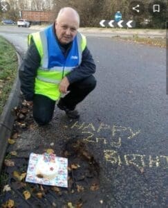 Man in high vis jacket measuring pothole