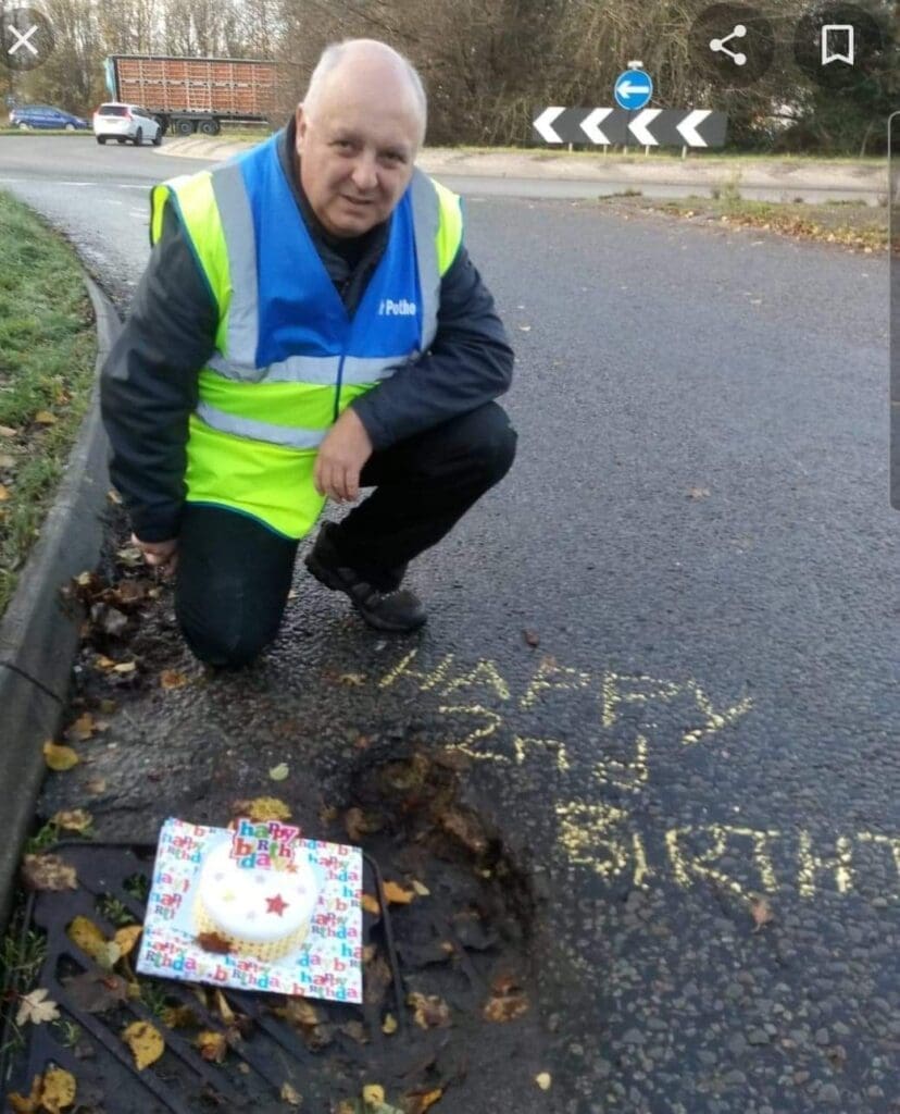 Man in high vis jacket measuring pothole
