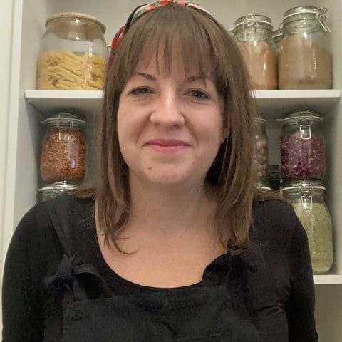 Woman straight mid length brown hair in front of kilner jars on shelves