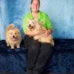 woman light green t short sitting smiling with two dogs