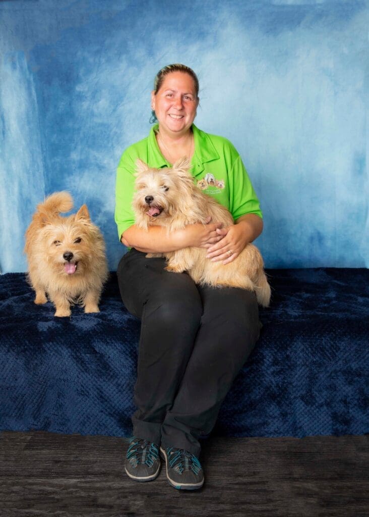 woman light green t short sitting smiling with two dogs