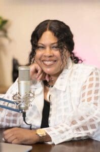 Black woman hair toed back sat in front of microphone cream blouse squares