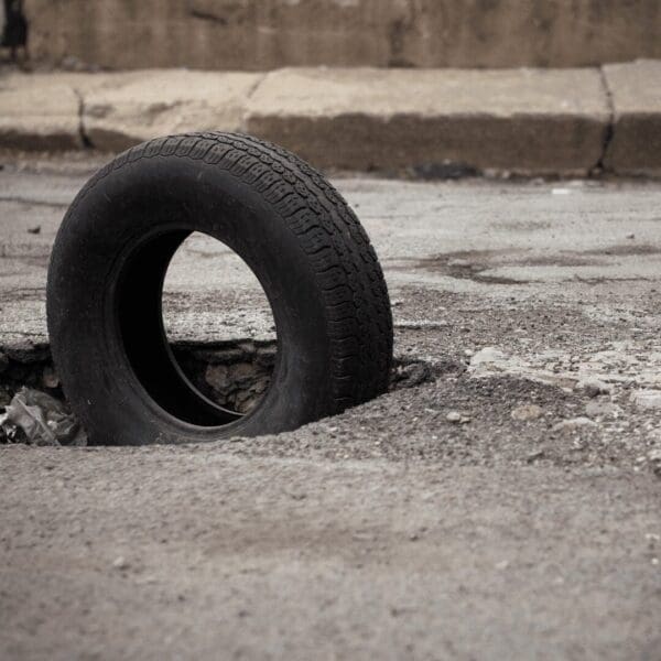 Big pothole in the road with tyre standing up in it