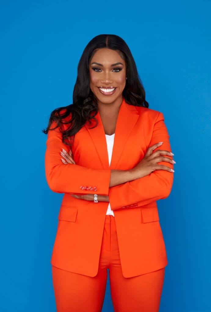 Black woman long black hair smiling in orange jacket and trousers
