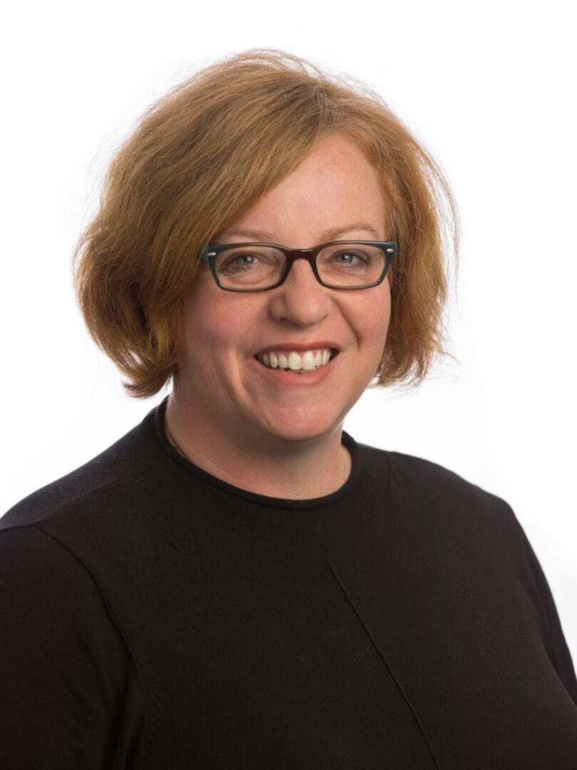 Head shot woman smiling in glasses short ginger/blond hair black top