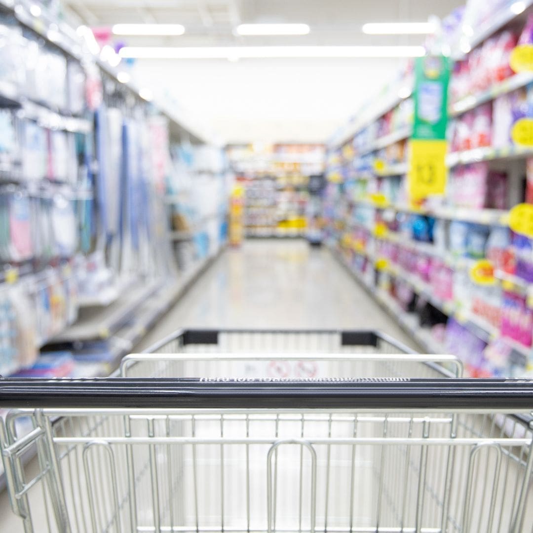 Trolley at start of supermarket aisle wit blurred products down each side