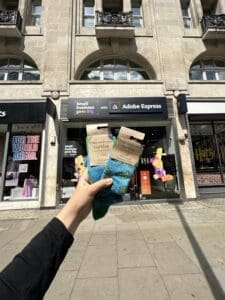 Hand holding two pairs of socks outside shop