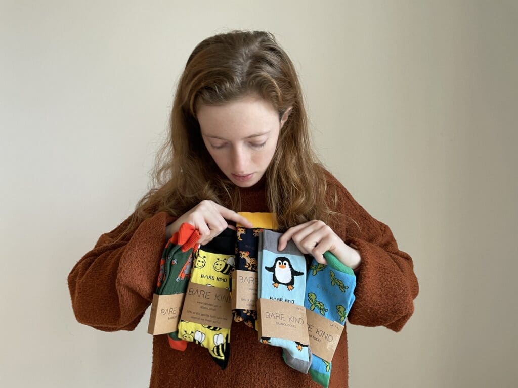 White woman light brown long hair holding and looking down at new socks with animals on them