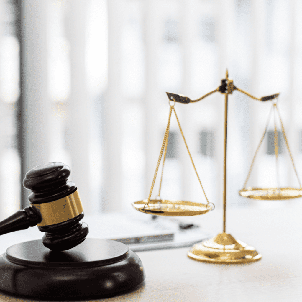 Gavel and brass scales in front of window blind