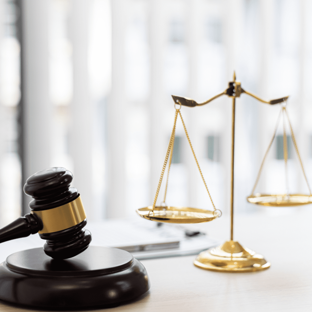 Gavel and brass scales in front of window blind