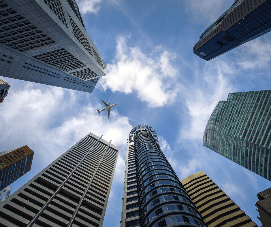 plane flying over sky scraper buildings