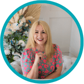 White woman mid 40s shoulder length blond straight hair smiling blue and pin spotted dress flowers in background green circle around image