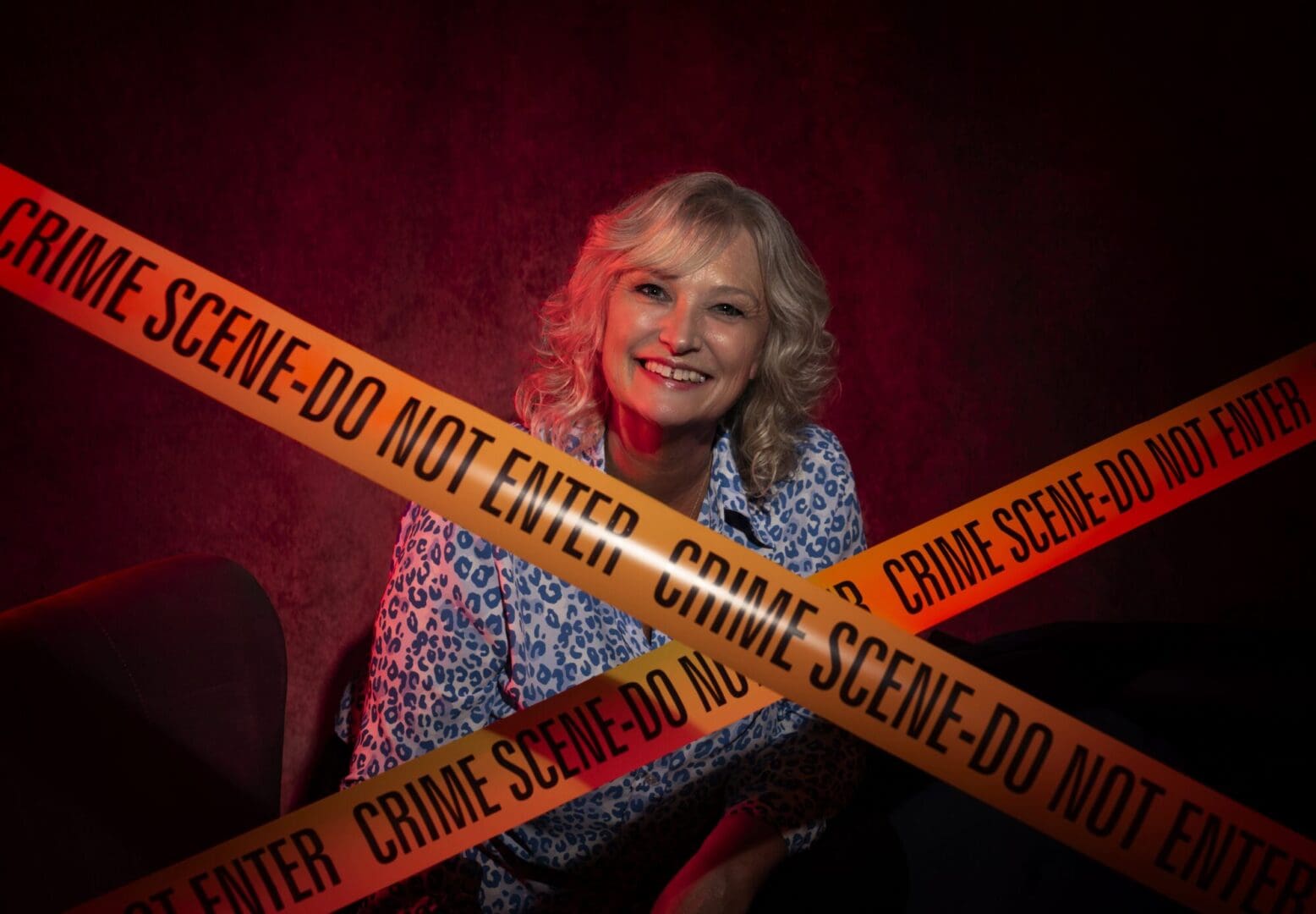 Crime scene tape crossed over in front of white woman smiling blond shoulder length curly hair blue and white spotted top