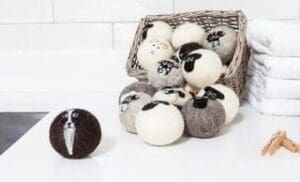 Basket of white and light grey balls of wool one darker brown on the white surface
