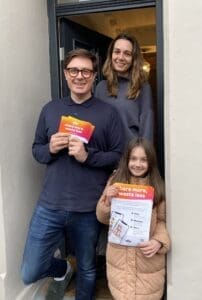 Man, woman, child in open doorway smiling.
