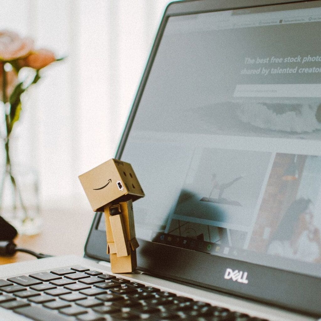 Little cardboard box with the Amazon smile on stick against screen on open laptop
