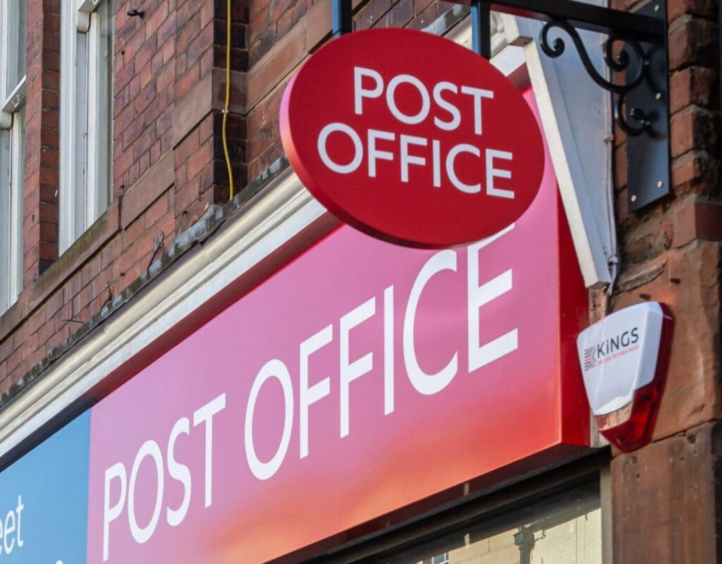 Post office shop sign against wall and one hanging
