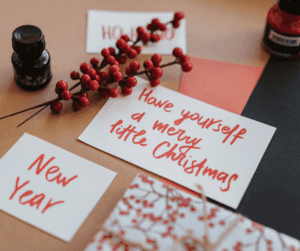 red twigs on table with three pieces of white card with Xmas messages