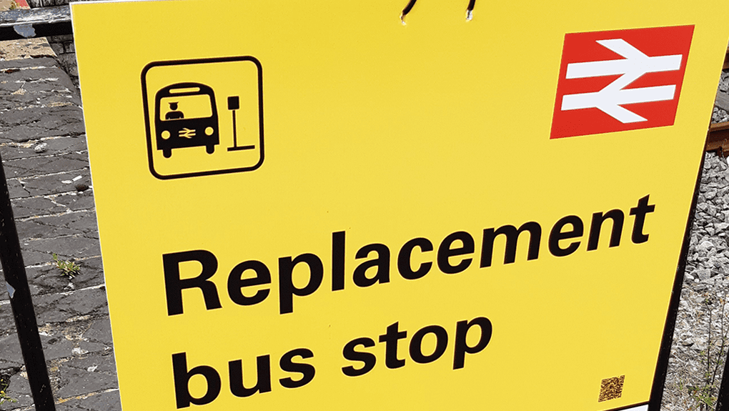 Yellow road sign with graphic of bus and words "Replacement bus stop"