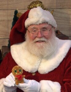 Santa headshot smiling man with white beard and glasses ref coat and cat with white fluffy collar and band on hat holding small duck yellow face big black eyes