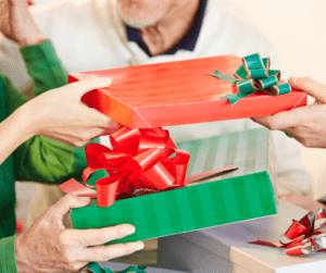 wihte man only see from chin down. white jumper exchanging three presents. Red with green bow. gren a white stripe and someone handing green and darker green stripe box red bow