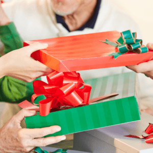wihte man only see from chin down. white jumper exchanging three presents. Red with green bow. gren a white stripe and someone handing green and darker green stripe box red bow