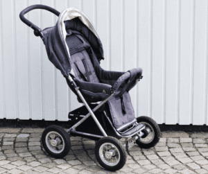 Empty buggy in front of white fence