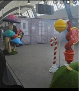 warehouse with couple with one red and white striped cane standing up, red coil and two blue umbrellas at the back