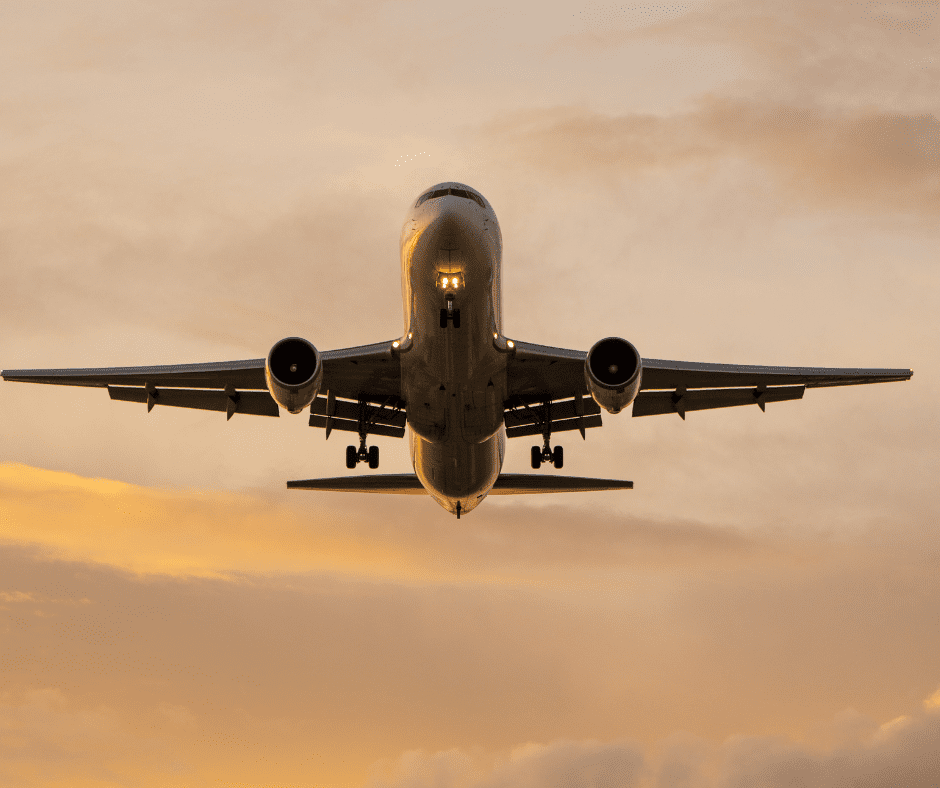 Passenger aeroplane in orange sky flying towards you
