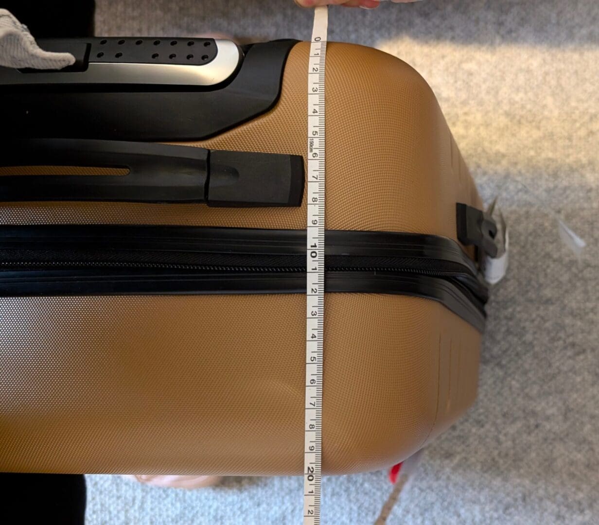 Light brown hard case black handle and black zip with tape measure across showing the measurements
