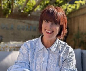 45 year old white woman light blue collared and buttoned shirt. Head shot smiling short straight reddish brown hair