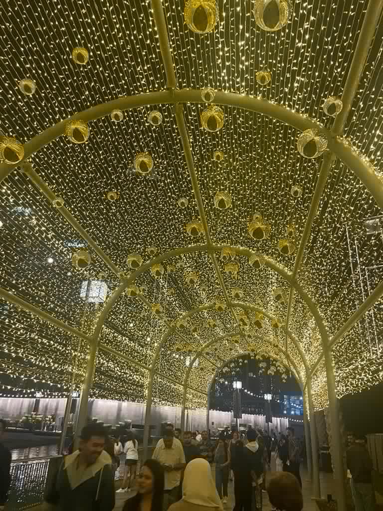 Tunnel of yellow lights people walking through smiling