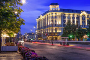 Big hotel on corner with lights on in front of road