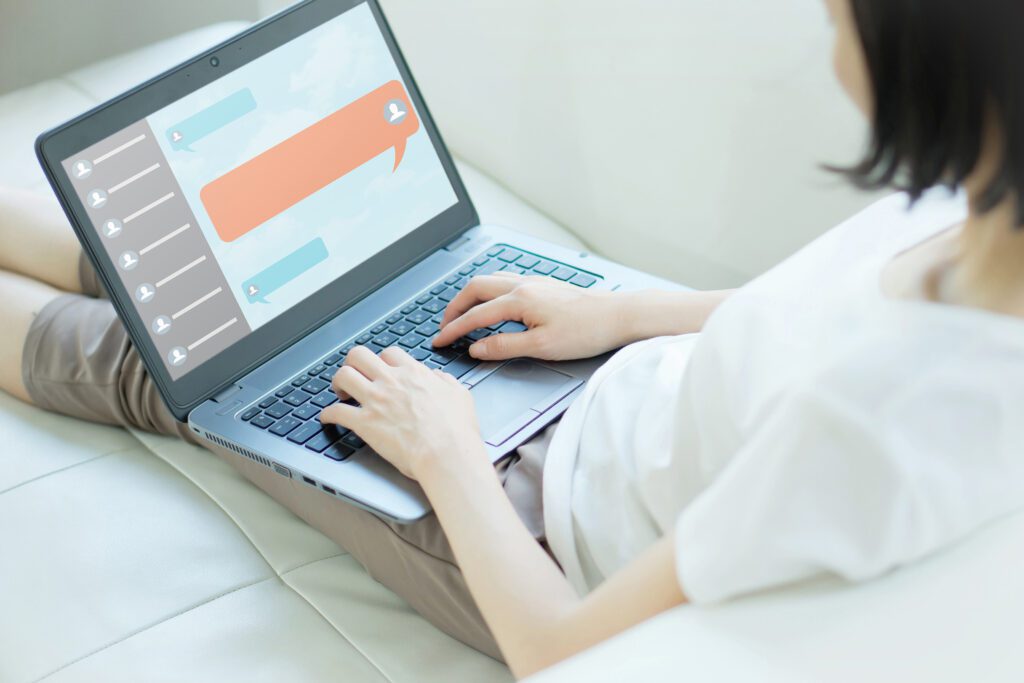 woman chat function in app on laptop screen looking for customer support onlinearms out both hands on lap top keyboard white arms person wearing white t shirt