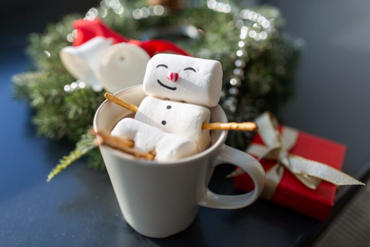 close up of marshmallow snowman taking bath in cup of coffee