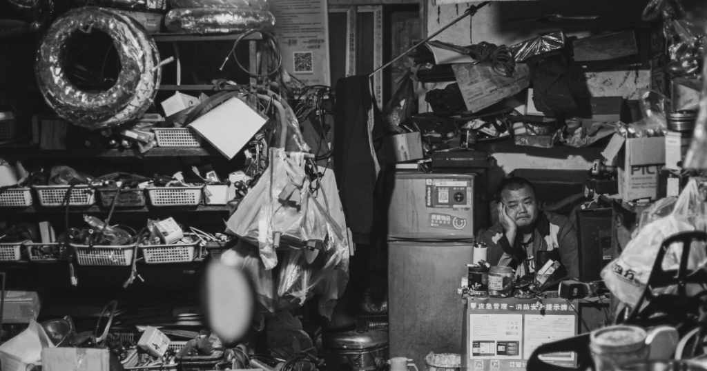 Black and white picture of a room full of clitter man trapped inside